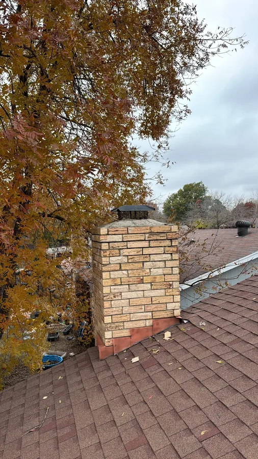 Old stone chimney with a small rusted cap before rebuild