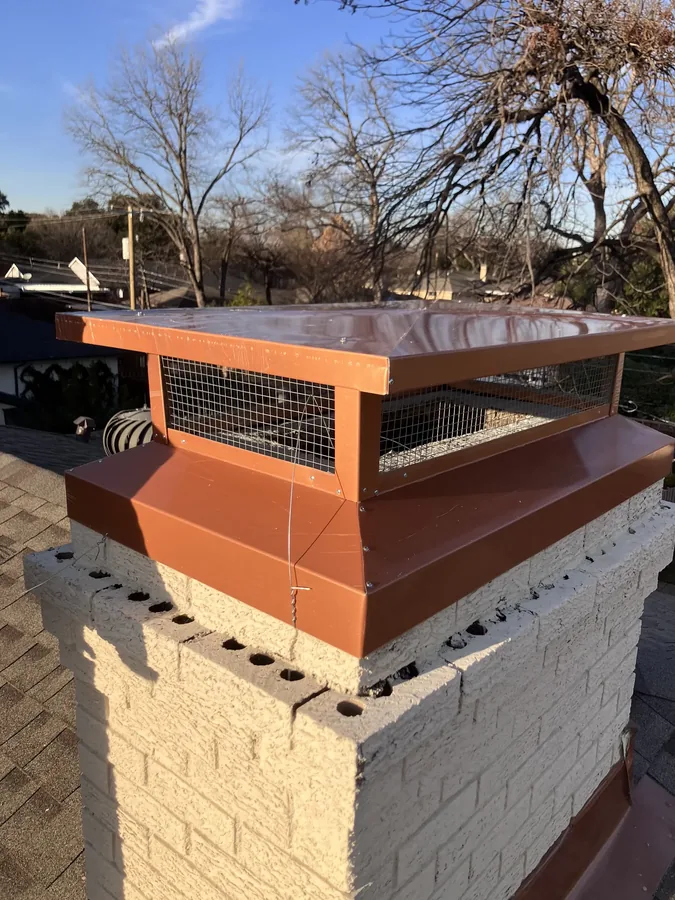 New copper-style chimney cap installed on a stucco chase, front view