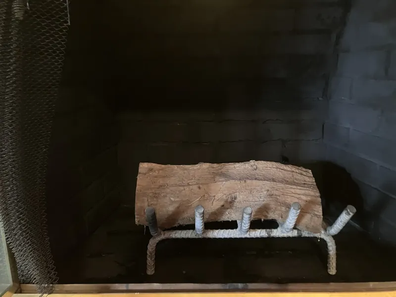 Sooty firebox interior with a log resting on a rebar grate