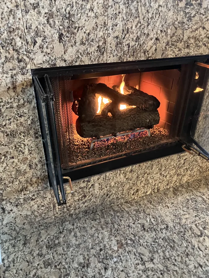 Gas fireplace insert lit and burning behind a granite surround