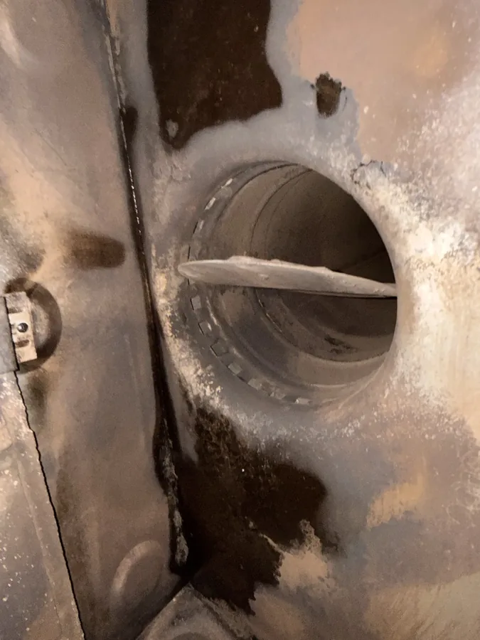 Close-up of a sooty flue collar and damper flap
