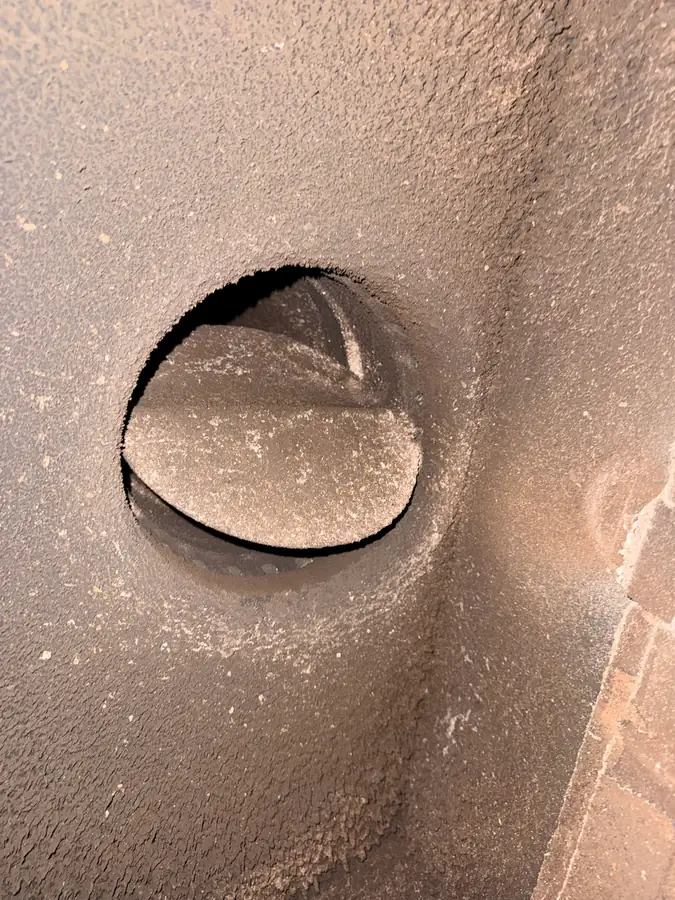 Chimney damper and flue opening coated in creosote and soot before sweeping