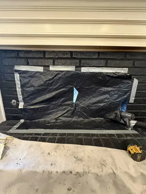 HEPA containment sheeting sealed over a fireplace opening before sweeping