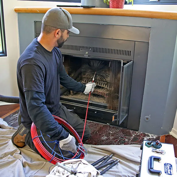 Technician sweeping an indoor fireplace with rods and a wire brush